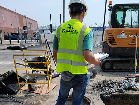 A project inspector is reviewing the manhole C19BA-203 installation for as-built documentation.