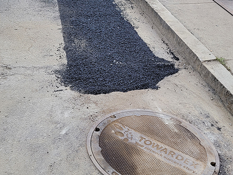 Placing the asphalt base binder for road surface restoration.  Complete restoration with top coat is performed separately at the end of the project.